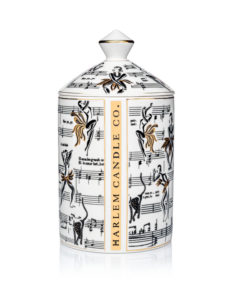 This is an image of our gold and white Deux Amours, ceramic candle with a lid. It features illustrations of Josephine Baker, and other original illustrations. The back of the candle has the words Harlem Candle Co on the vessel in gold and black.