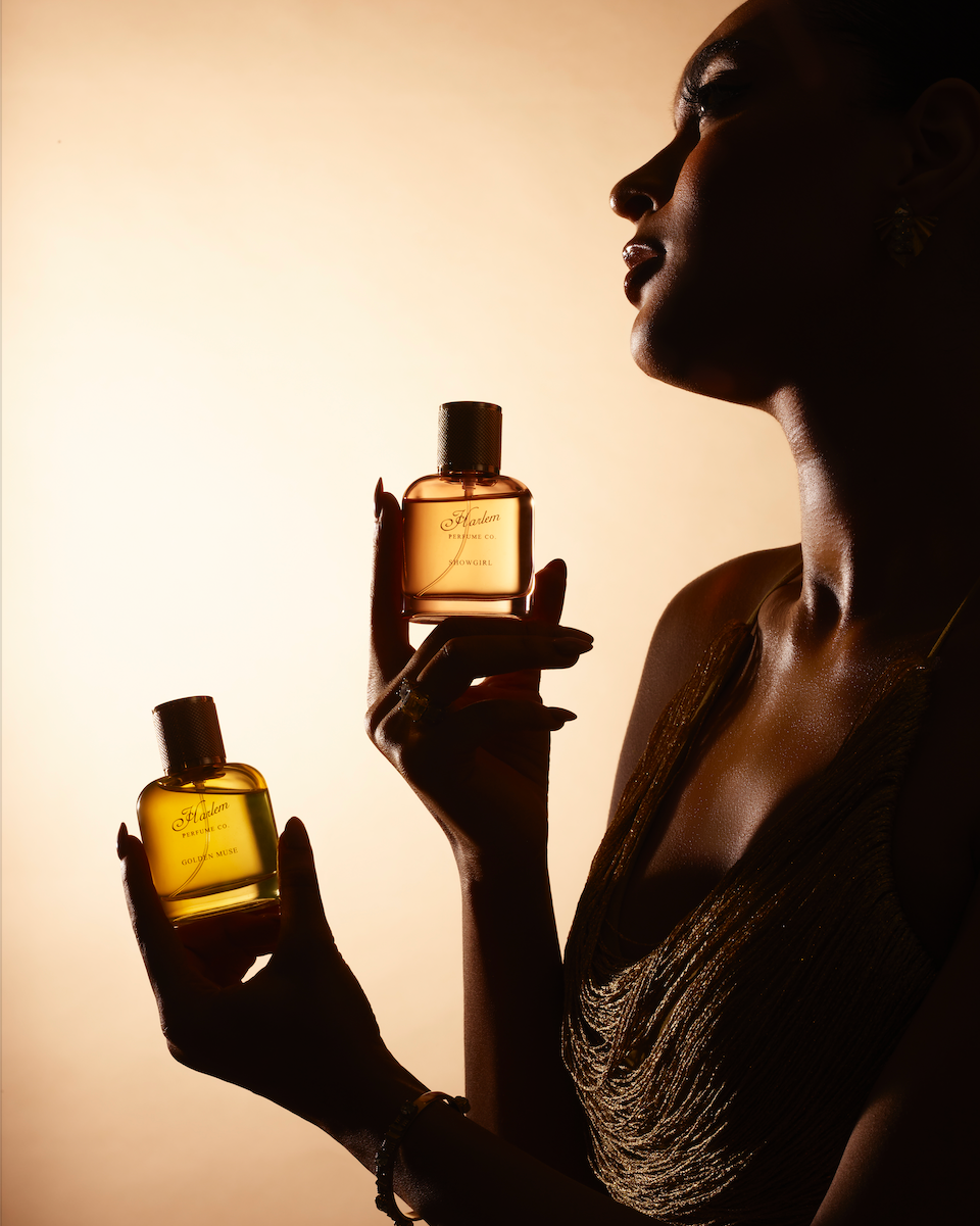 Silhouette of a woman holding two perfume bottles against a beige background