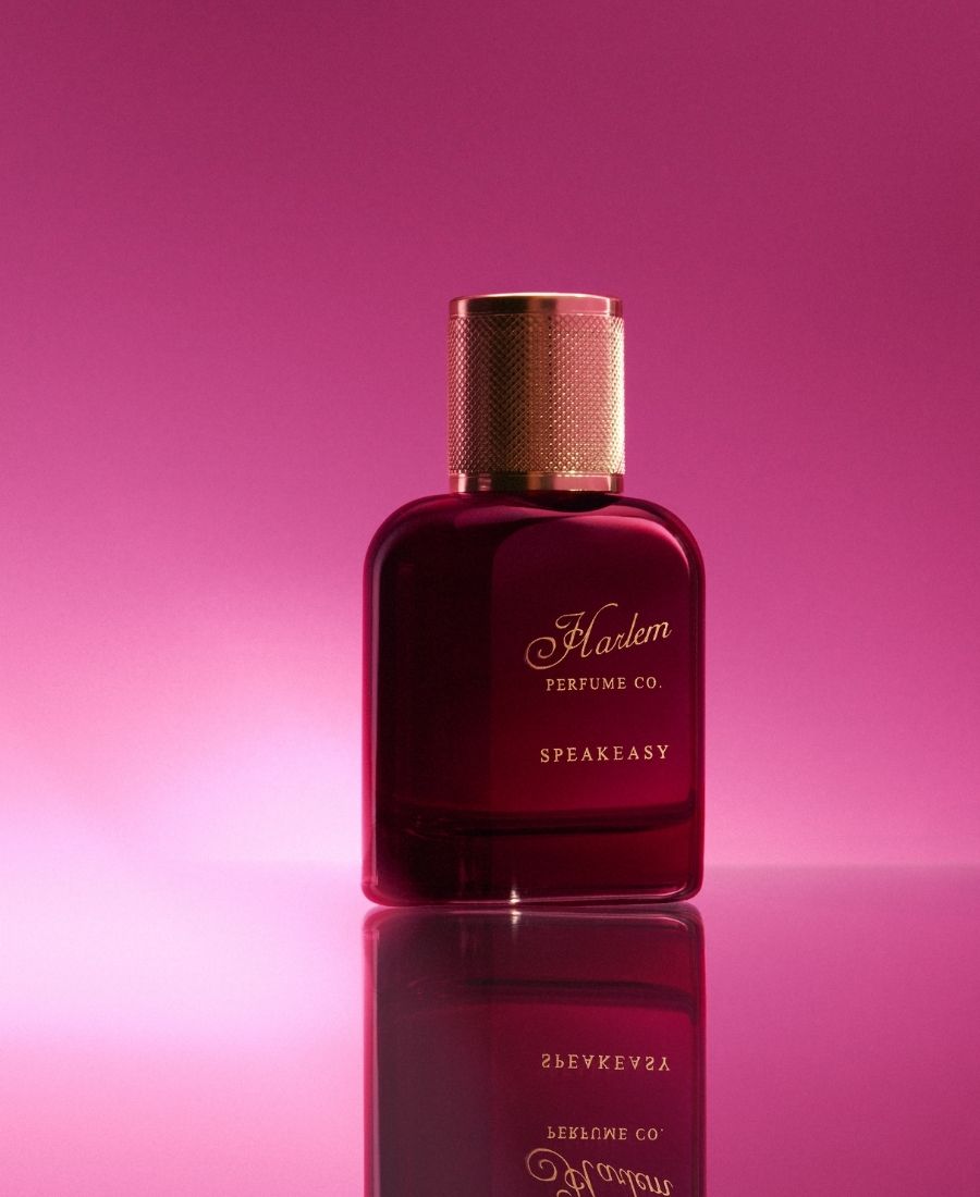 Burgundy perfume bottle with gold cap on a pink gradient background