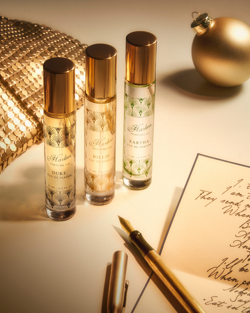 Three perfume bottles with gold caps on a surface with a decorative ball and handwritten text.