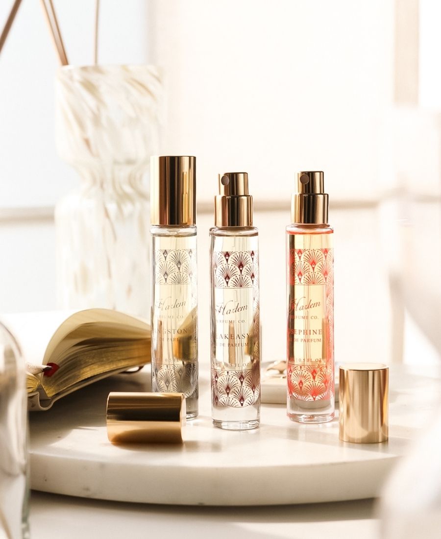 This is an image of three travel size perfumes  with gold caps on a white surface.