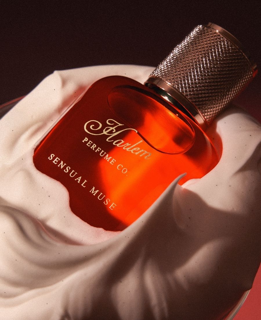 Harlem Perfume Co. Sensual Muse perfume bottle on a white surface with a dark background