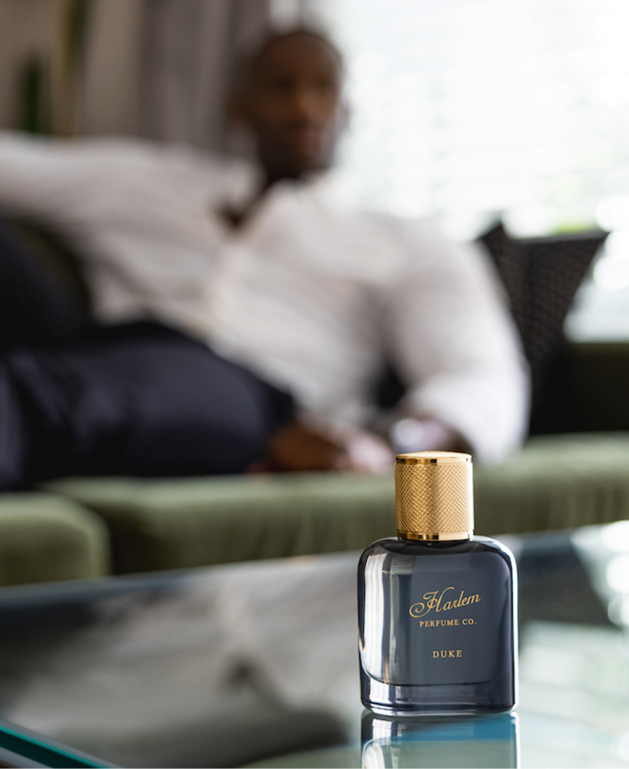 This is an image of our Duke eau de parfume on a glass table with a male model in the background.